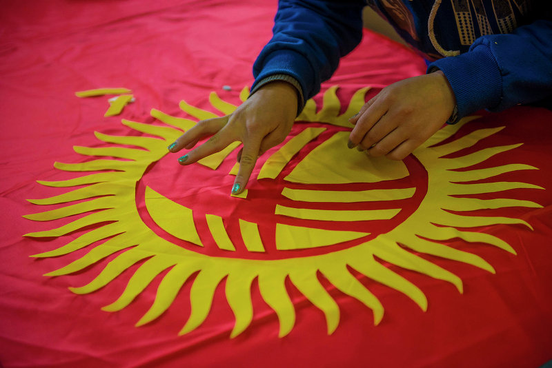 Государственный флаг Кыргызстана в центре которого полотнища изображен тундук кыргызской юрты в обрамлении сорока солнечных лучей.