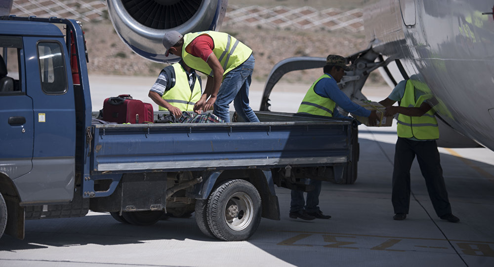 Сотрудники аэропорта загружают вещи пассажиров в самолет. Архивное фото