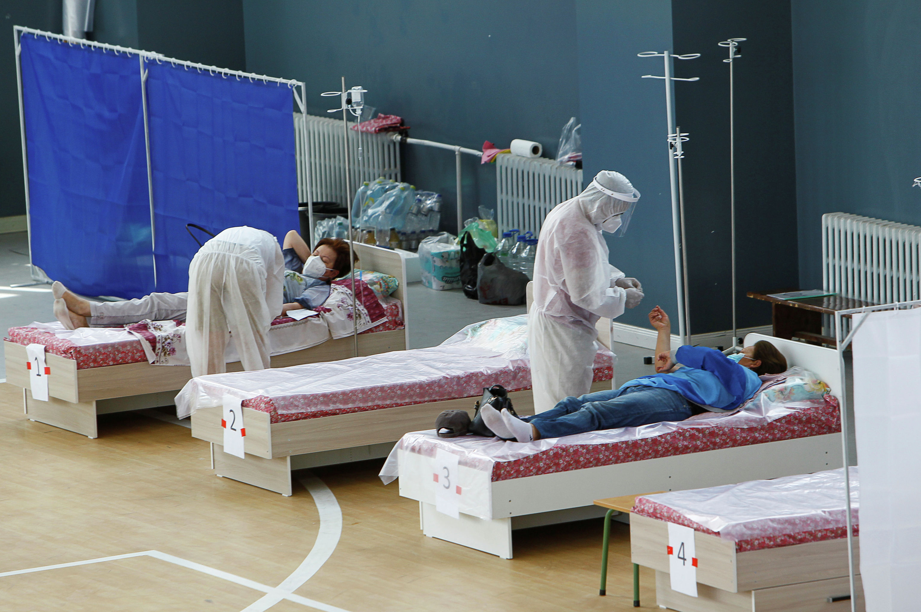 Медицинские специалисты, носящие средства индивидуальной защиты (СИЗ), лечат пациентов в дневном стационаре, который расположен в школьном спортзале в Бишкеке. 16 июля 2020 года