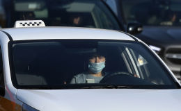 Водитель в защитной маске за рулем такси на одной из улиц в Москве. Архивное фото Водитель в защитной маске за рулем такси на одной из улиц в Москве. Архивное фото
