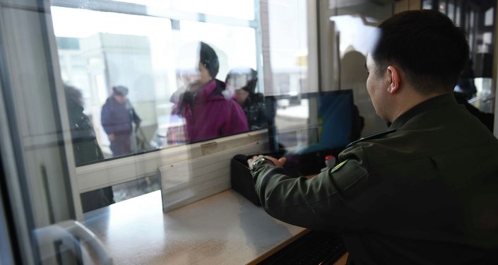 Сотрудник контрольно пропускного пункта кыргызско-казахской границы проверяет документы у граждан. Архивное фото