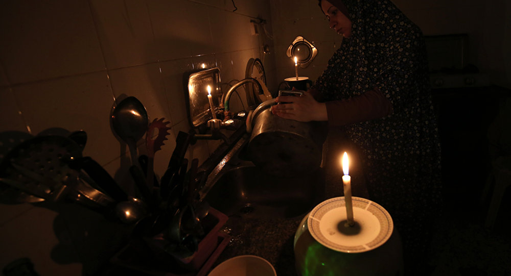 Женщина моет посуду при свечах в своем доме. Архивное фото