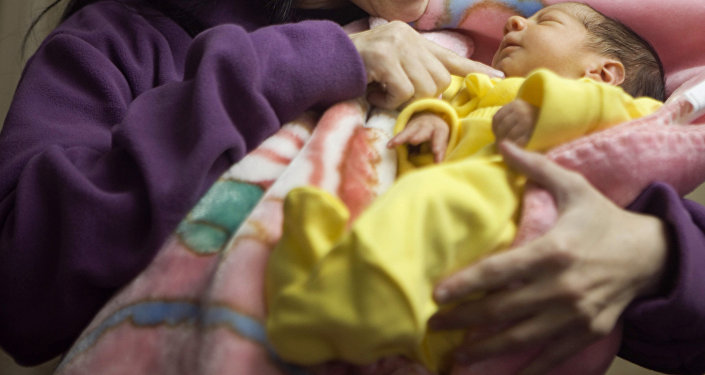Женщина с новорожденным ребенком в руке. Архивное фото