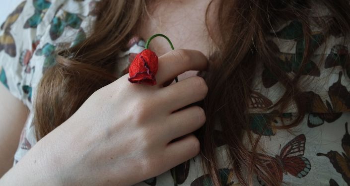 Девушка держит цветок в руке. Иллюстративное фото