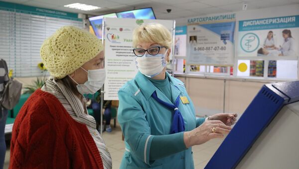 Сотрудница поликлиники помогает посетительнице получить талон к врачу. Архивное фото - Sputnik Кыргызстан