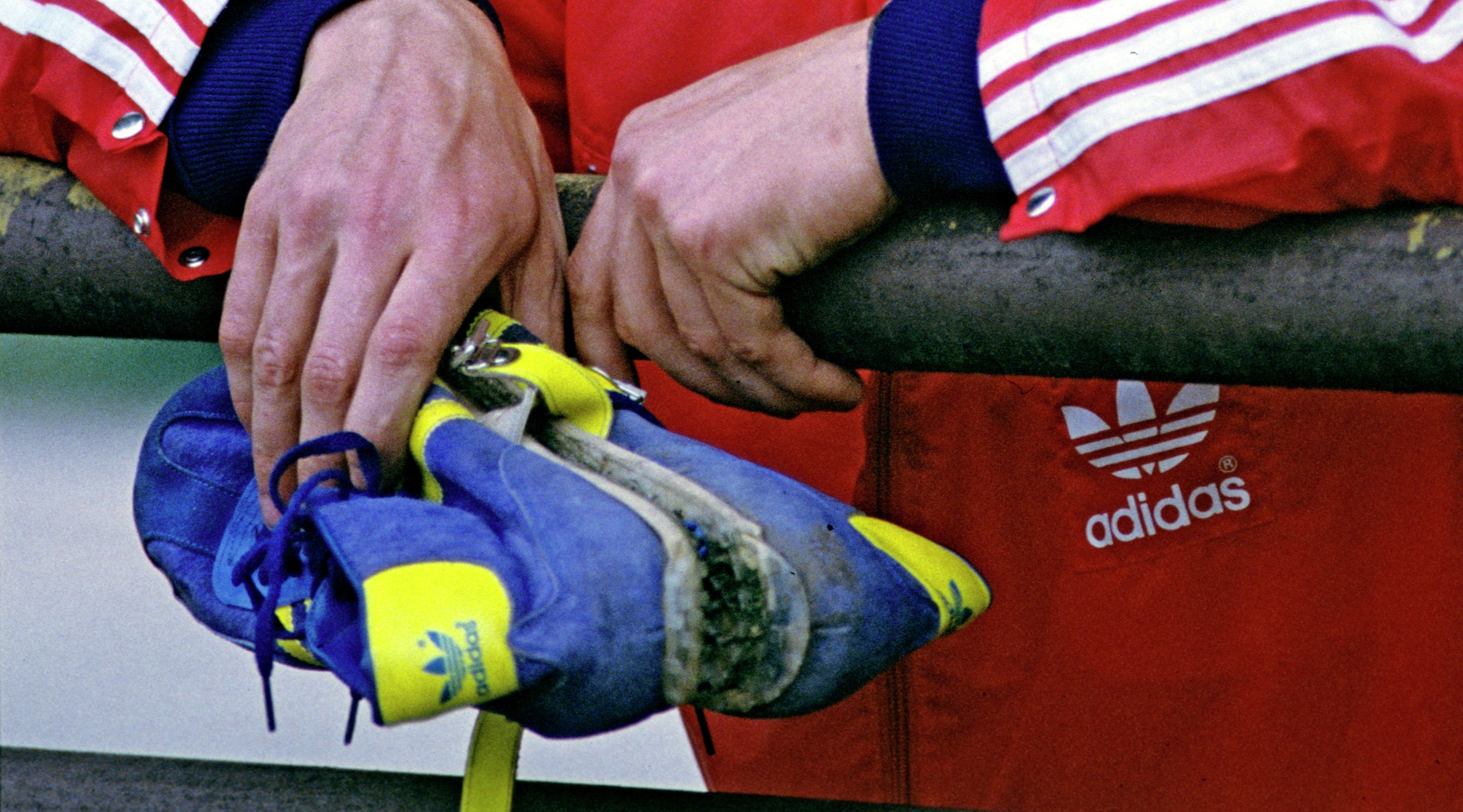 Советский спортсмен держит в руке кроссовки Adidas.
