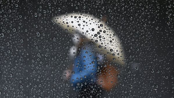 Женщина с зонтом идет по улице во время дождя. Архивное фото - Sputnik Кыргызстан