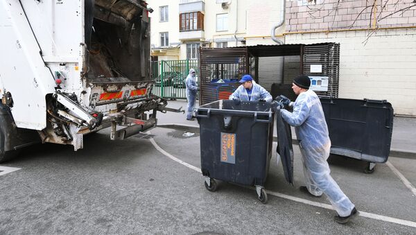Сотрудники муниципалитета выгружают содержимое мусорного контейнера в мусоровоз. Архивное фото - Sputnik Кыргызстан
