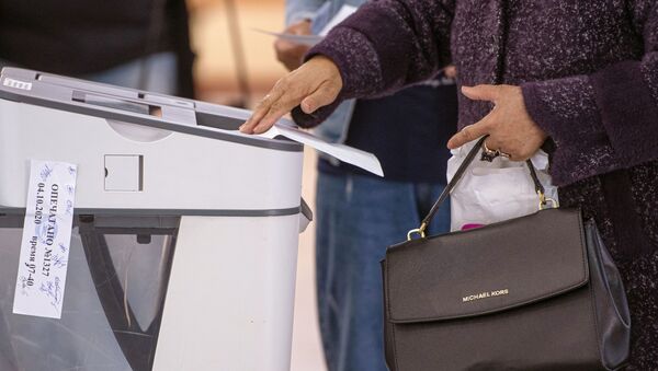 Женщина опускает бюллетень в урну для голосования на избирательном участке №1327 в Бишкеке в ходе голосования на выборах седьмого созыва ЖК - Sputnik Кыргызстан