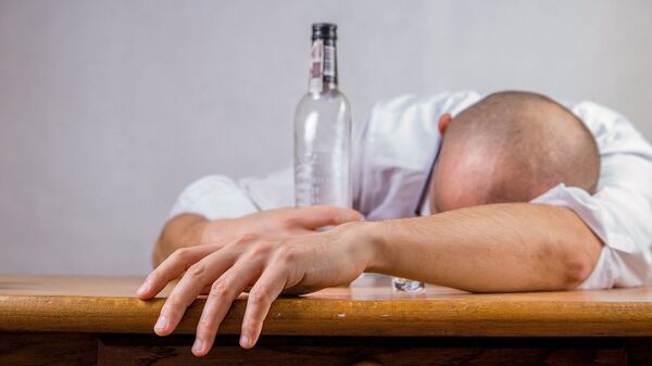 Мужчина лежит на столе с бутылкой спиртного в руках. Иллюстративное фото - Sputnik Кыргызстан