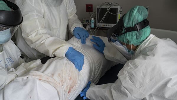 Медицинский персонал в СИЗах оборачивает покойного пациента простынями. Архивное фото - Sputnik Кыргызстан