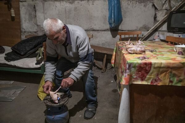 Тоолуу Карабахтын жашоочусу Шуши шаарындагы өз үйүнүн жер төлөсүндө көгүчкөндүн этин тамакка кошууга даярдап жатат - Sputnik Кыргызстан