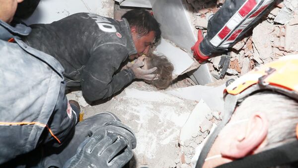 Спасатели вытаскивают ребенка из-под завала в результате землетрясения в Измире, Турция - Sputnik Кыргызстан