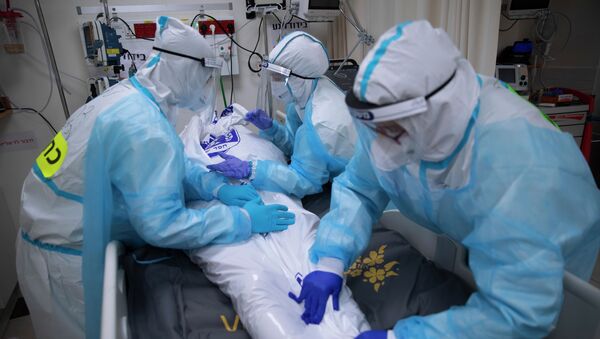 Медицинский персонал в СИЗ прикрывает тело мужчины, умершего от COVID-19 - Sputnik Кыргызстан
