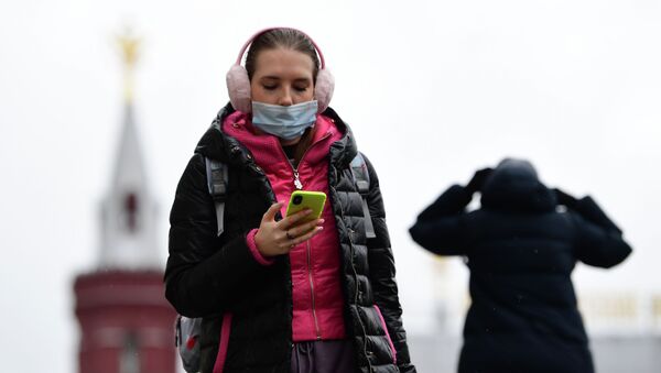 Девушка в защитной маске на Манежной площади в Москве с телефоном в руках - Sputnik Кыргызстан