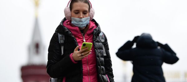 Девушка в защитной маске на Манежной площади в Москве с телефоном в руках Девушка в защитной маске на Манежной площади в Москве с телефоном в руках - Sputnik Кыргызстан