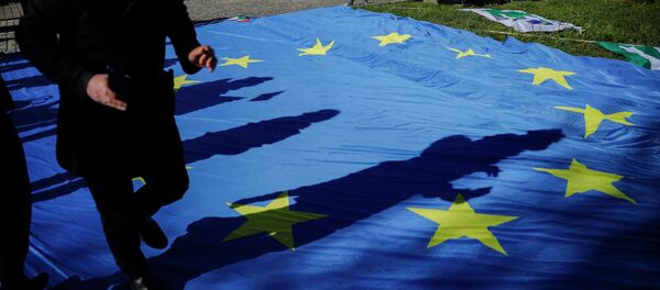 Мужчина в медицинской маске и ребенок с флагом на фоне разложенного на земле флага Европейского союза. Архивное фото - Sputnik Кыргызстан