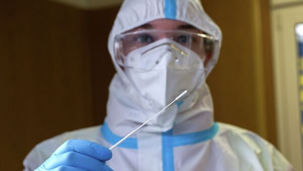 Медицинский работник в СИЗ держит мазок для тестирования на COVID-19 - Sputnik Кыргызстан