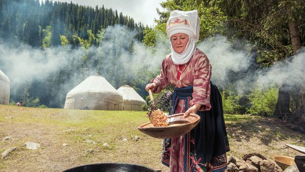 Женщина в национальной кыргызской одежде готовит боорсоки. Архивное фото - Sputnik Кыргызстан