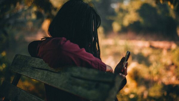 Девочка на скамейке со смартфоном в руке. Иллюстративное фото - Sputnik Кыргызстан