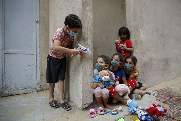 Пакистанские дети в защитных масках играют возле своего дома в Газе - Sputnik Кыргызстан