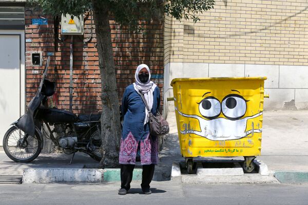 Женщина в защитной маске у разрисованного мусорного бака в Тегеране, Иран - Sputnik Кыргызстан