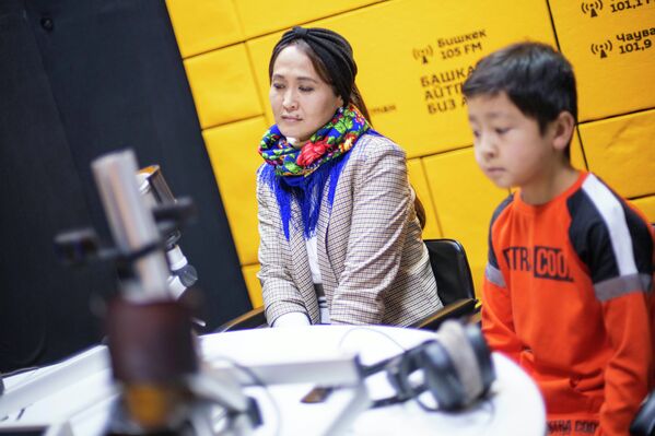  Элмирбек акындын жубайы   Нурзат уулу Адылхан менен    Spuntik Кыргызстандын студиясында. "Убакыт дарылайт деп коет го, бирок убакыт дарылабай эле күн өткөн сайын сагынычыбыз күч алгандан күч алды", - дейт Нурзат айым.  - Sputnik Кыргызстан