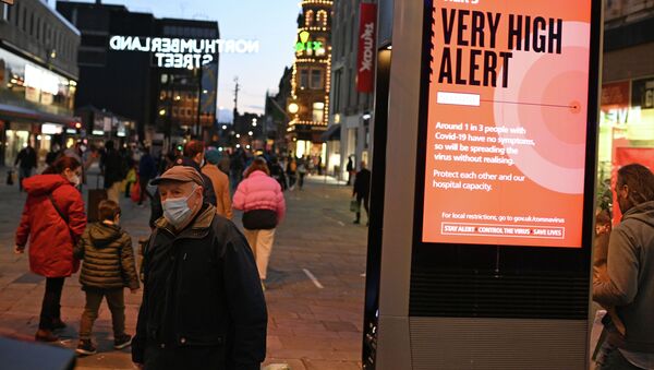 Пешеход в защитной маске проходит мимо информационного табло о правилах борьбы с распространением COVID-19 в центре Ньюкасл-апон-Тайн (Англия) - Sputnik Кыргызстан