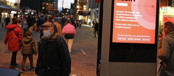 Пешеход в защитной маске проходит мимо информационного табло о правилах борьбы с распространением COVID-19 в центре Ньюкасл-апон-Тайн (Англия) - Sputnik Кыргызстан