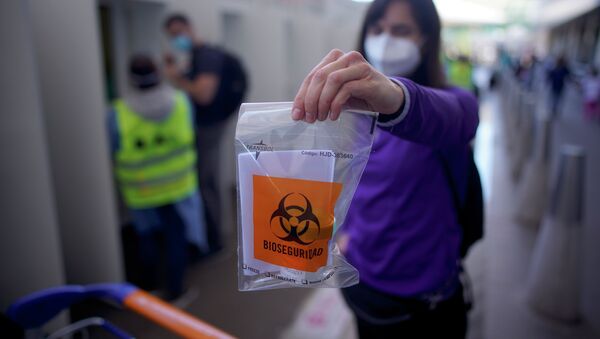 Женщина показывает пластиковый пакет с надписью биологическая опасность для теста на COVID-19 - Sputnik Кыргызстан