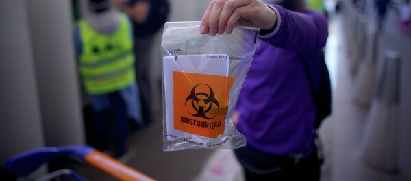 Женщина показывает пластиковый пакет с надписью биологическая опасность для теста на COVID-19 - Sputnik Кыргызстан