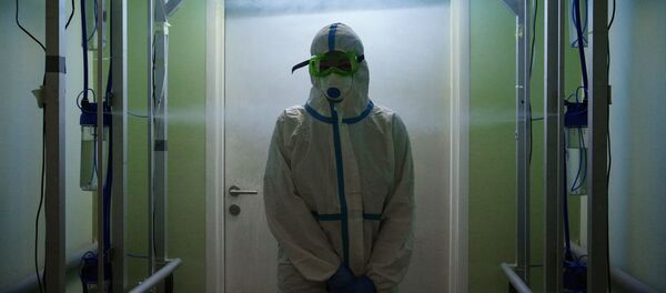 Медик в защитном противоэпидемическом костюме проходит санитарную обработку - Sputnik Кыргызстан
