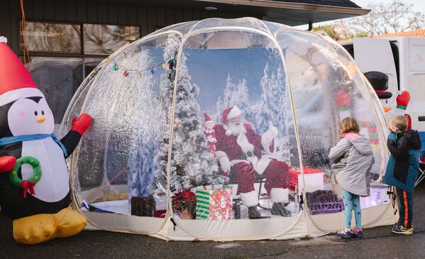 Санта-Клаустун костюмун кийген киши Сиэтл шаарында Рождествого карата жасалган көчөдө балдар менен баарлашып отурат - Sputnik Кыргызстан