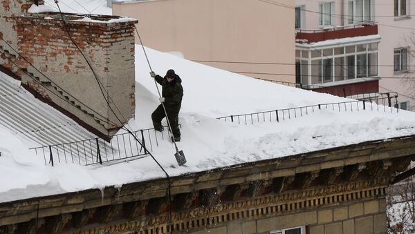 Коммуналдык кызматкер карды турак үйдүн чатырынан тазалап жатат. Архив - Sputnik Кыргызстан