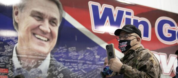 Мужчина слушает сенатора Дэвида Пердью (штат Джорджия), выступающего перед толпой на предвыборном митинге в Атланте - Sputnik Кыргызстан