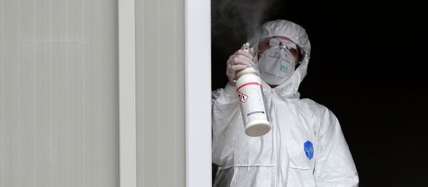 Медицинский работник в защитном костюме распыляет дезинфицирующее средство - Sputnik Кыргызстан