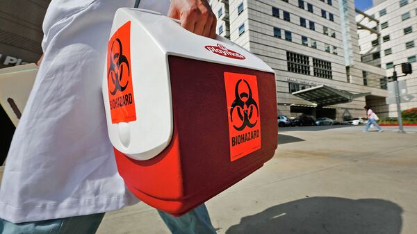 Медицинский сотрудник несет портативный холодильник с этикеткой биологической опасности. Архивное фото - Sputnik Кыргызстан