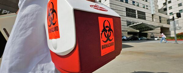 Медицинский сотрудник несет портативный холодильник с этикеткой биологической опасности. Архивное фото - Sputnik Кыргызстан