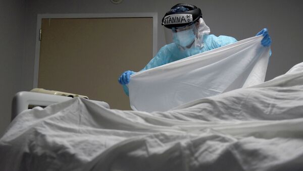 Медицинский сотрудник накрывает простыней тело пациента, умершего от COVID-19 - Sputnik Кыргызстан