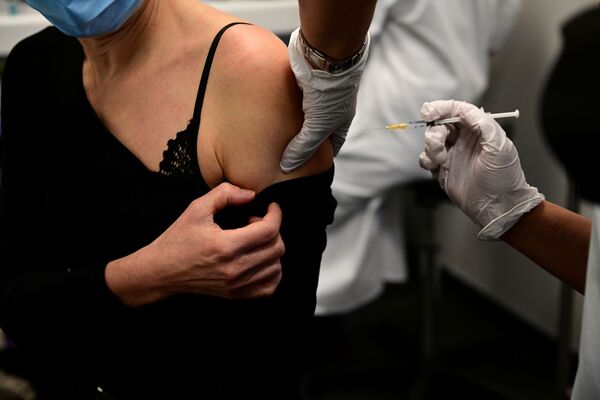 Женщина получает вакцину от COVID-19 во время кампании вакцинации медицинских работников в центре вакцинации в Париже - Sputnik Кыргызстан