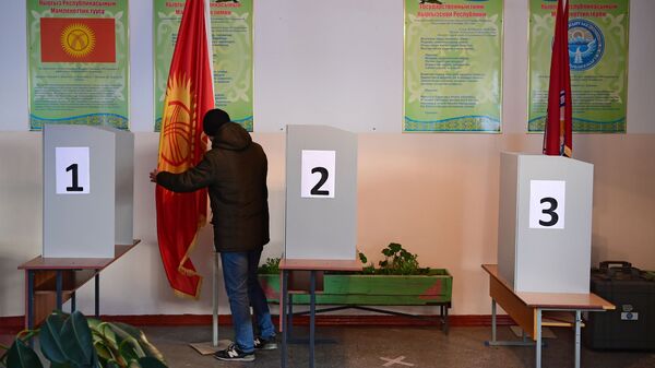 Мужчина расставляет флагштоки на избирательном участке в Бишкеке. - Sputnik Кыргызстан