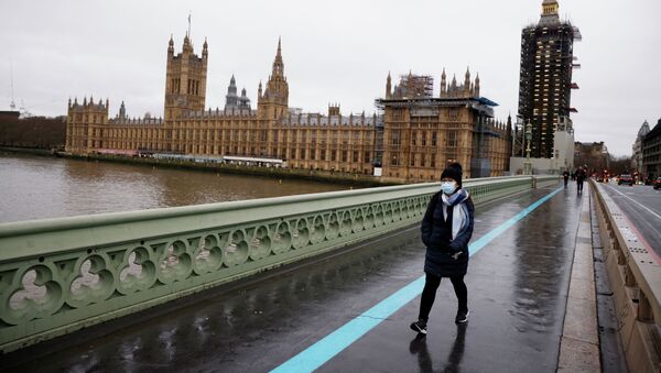 Женщина в маске идет по Вестминстерскому мосту мимо здания Парламента в Лондоне. Архивное фото - Sputnik Кыргызстан