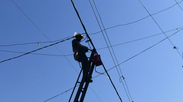 Техник энергетической компании ремонтирует линию электропередачи. Архивное фото - Sputnik Кыргызстан