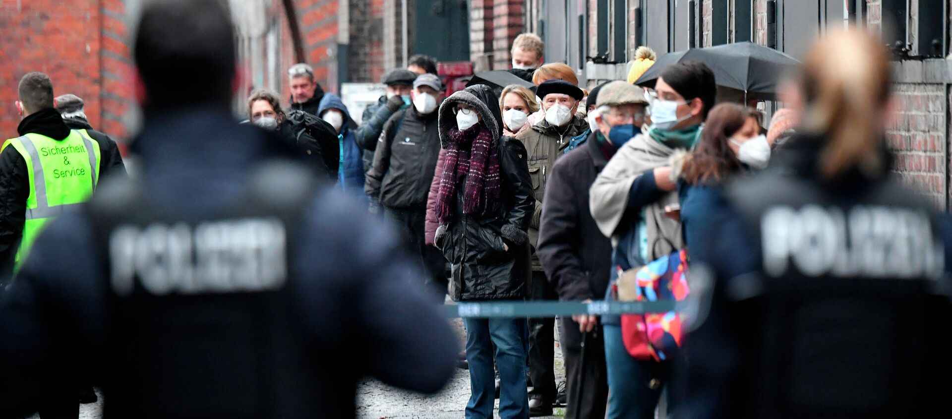 Сотрудники полиции наблюдают за очередью людей в масках у центра вакцинации в здании Берлинской арены  - Sputnik Кыргызстан, 1920, 30.01.2021