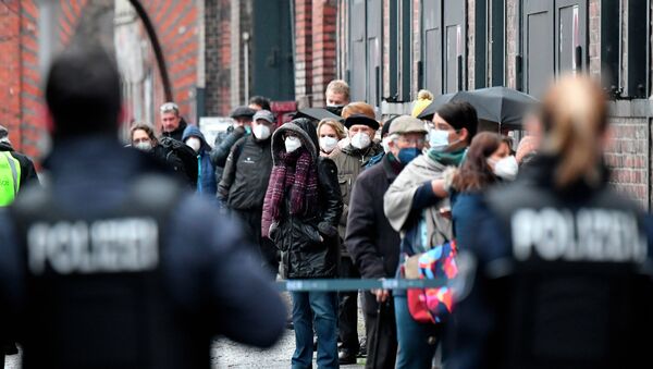 Сотрудники полиции наблюдают за очередью людей в масках у центра вакцинации в здании Берлинской арены  - Sputnik Кыргызстан