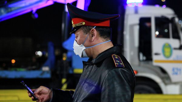 Сотрудник полиции в защитной маске держит смартфон. Архивное фото - Sputnik Кыргызстан