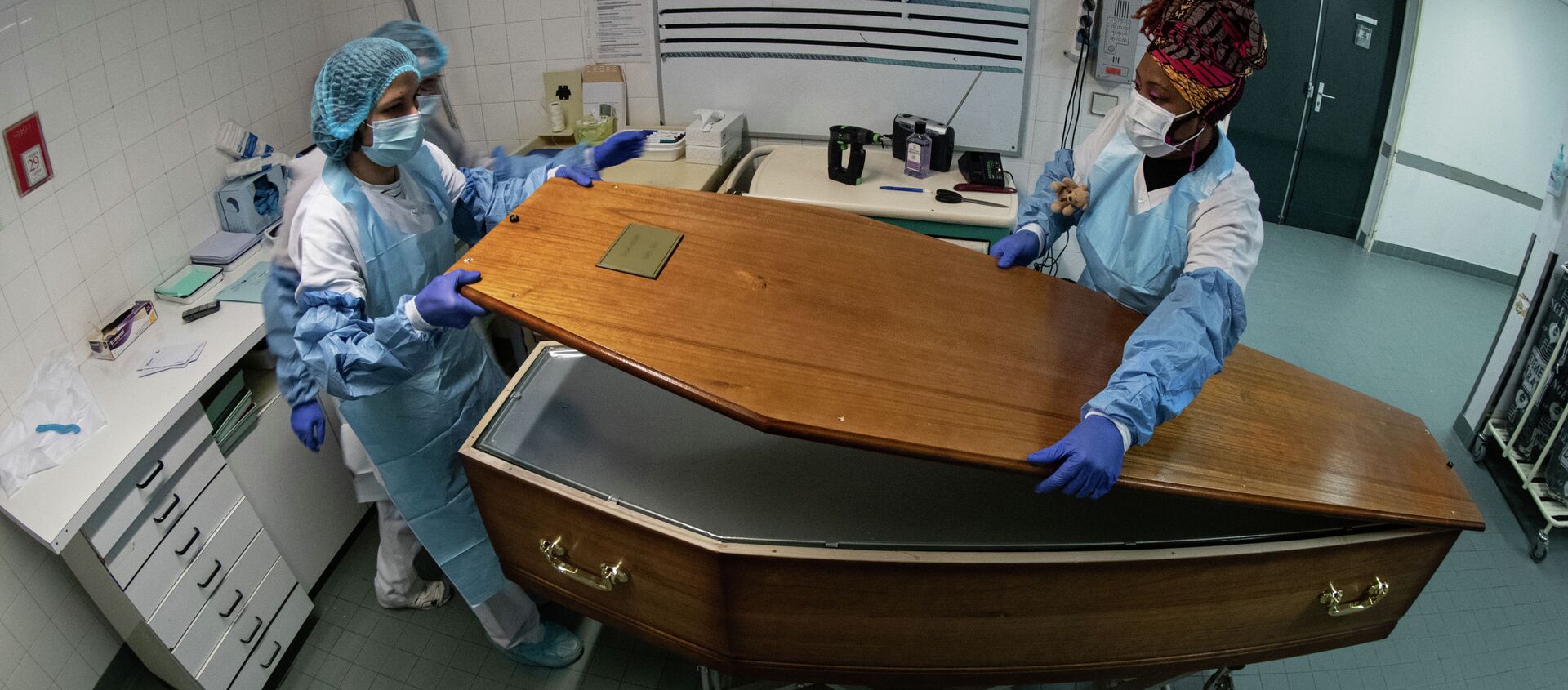 Медицинский персонал закрывает гроб с телом пациента, умершего от Covid-19, в морге больницы - Sputnik Кыргызстан, 1920, 04.02.2021