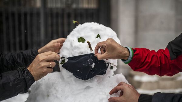 Люди надевают маску на слепленного снеговика. Архивное фото - Sputnik Кыргызстан