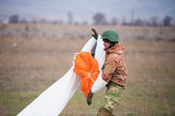 Секирип жерге конгон жоокер парашютун жыйнап жатат - Sputnik Кыргызстан