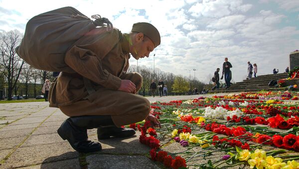 Мужчина возлагает цветы на мемориальном комплексе советских воинов-освободителей в парке Победы в Риге. Архивное фото - Sputnik Кыргызстан